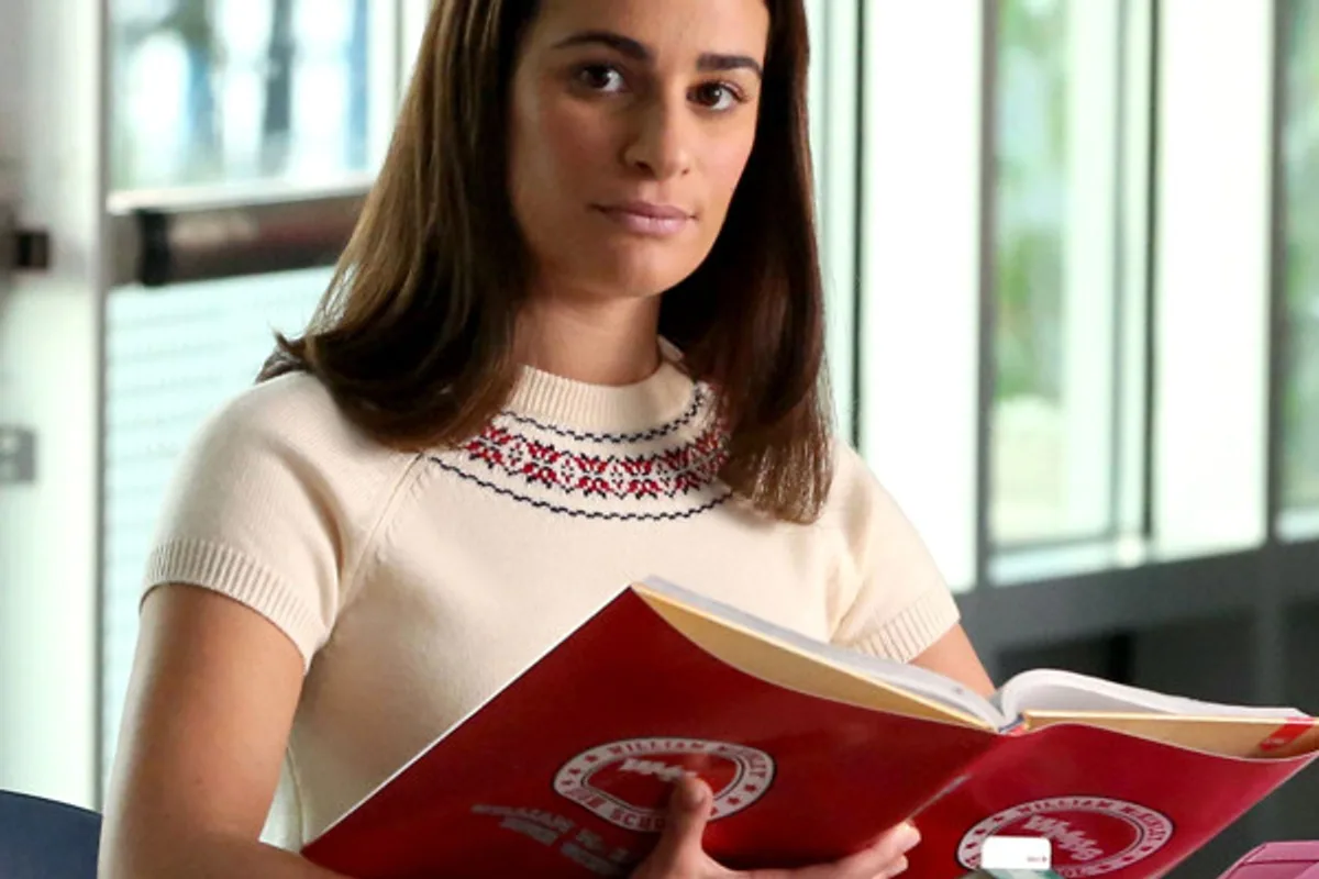 Rachel Berry dans une scène de la dernière saison de Glee, avec un classeur rouge posé devant elle