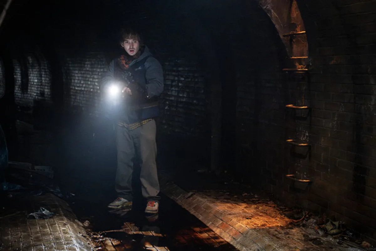 Bryan explore un passage souterrain sombre à la lampe torche dans Resident Evil